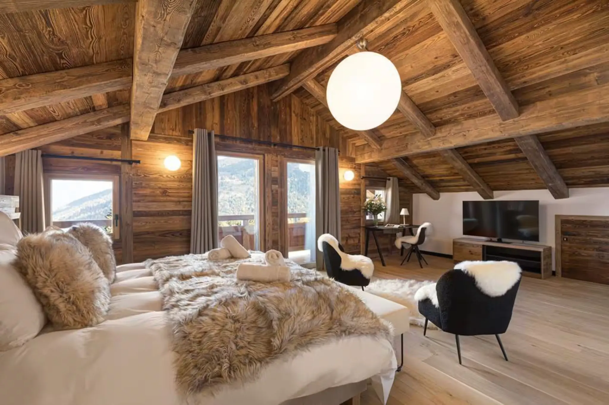 The supplied chalet bedroom with exposed timber beams, mountain views and a private balcony.